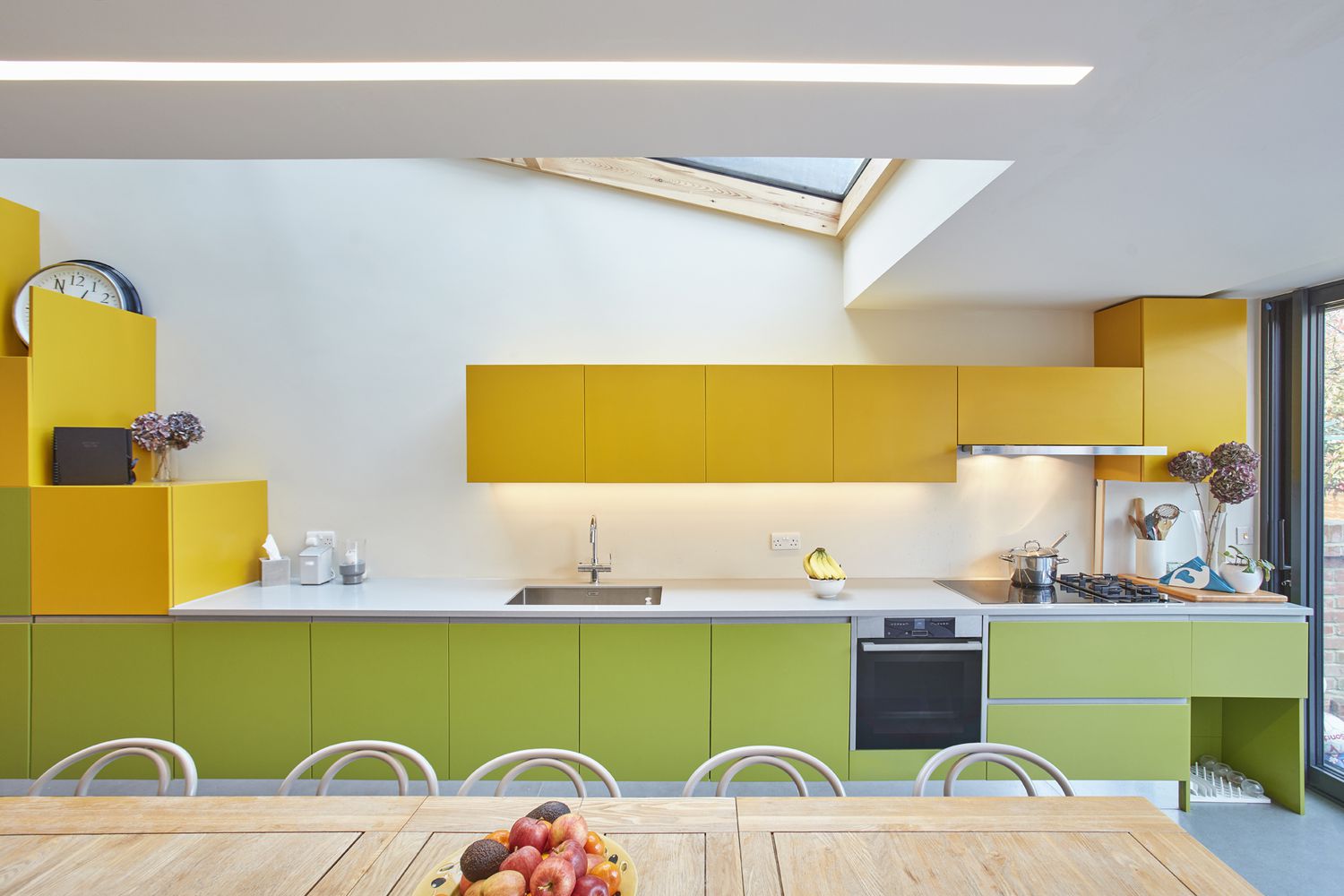 Cozinha com armários verdes embaixo do balcão e armários superiores amarelos