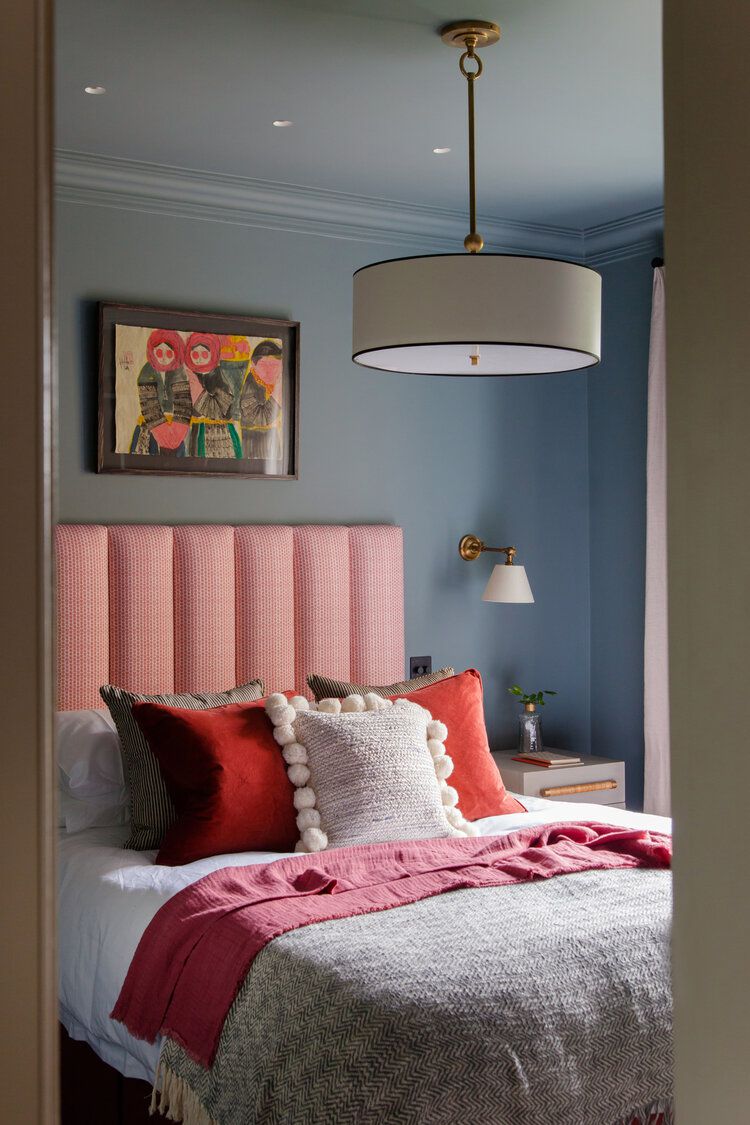 Jugendzimmer mit staubblauen Wänden und rosa und roten Bettakzenten.