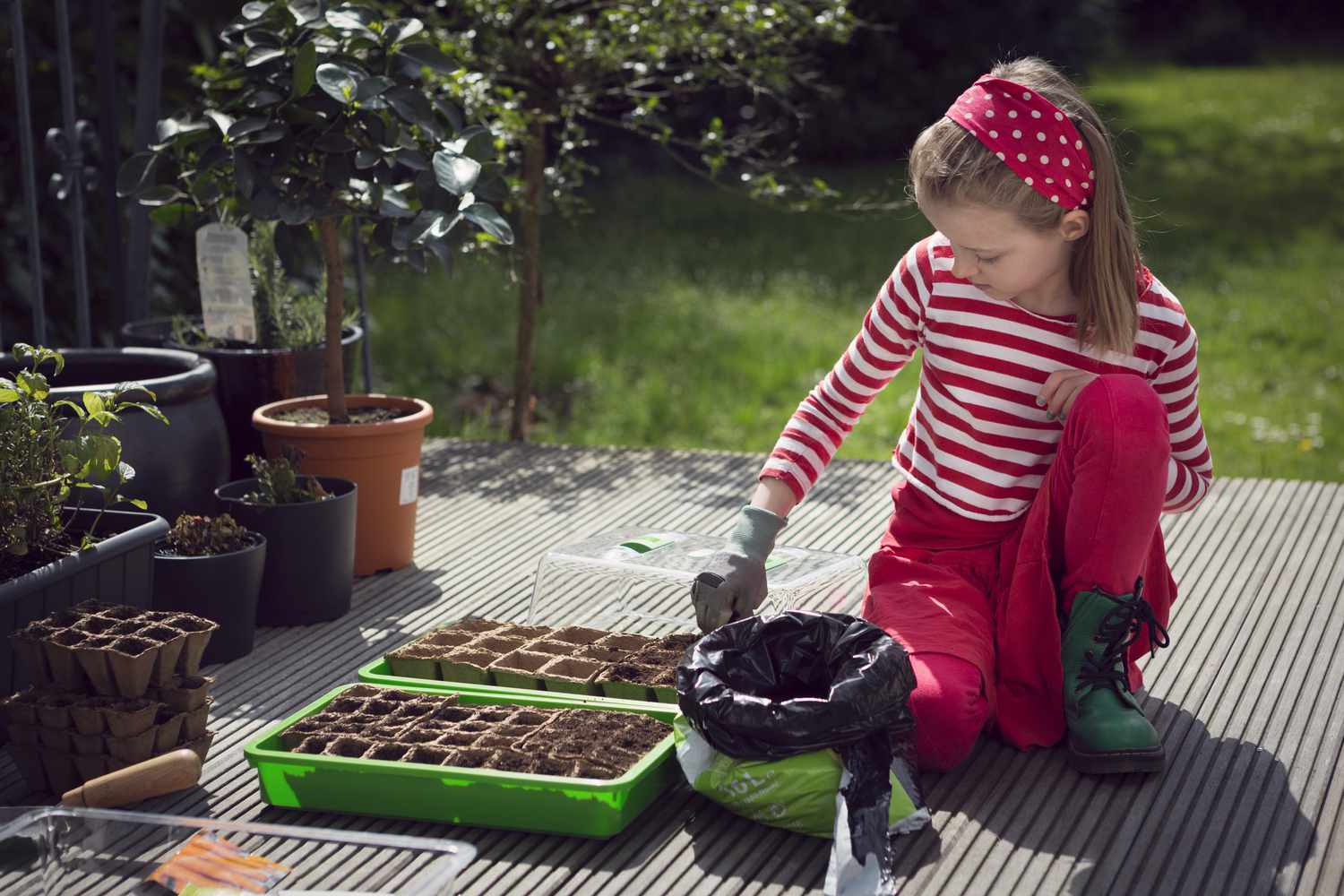 Niña plantando semillas en recipientes biodegradables.