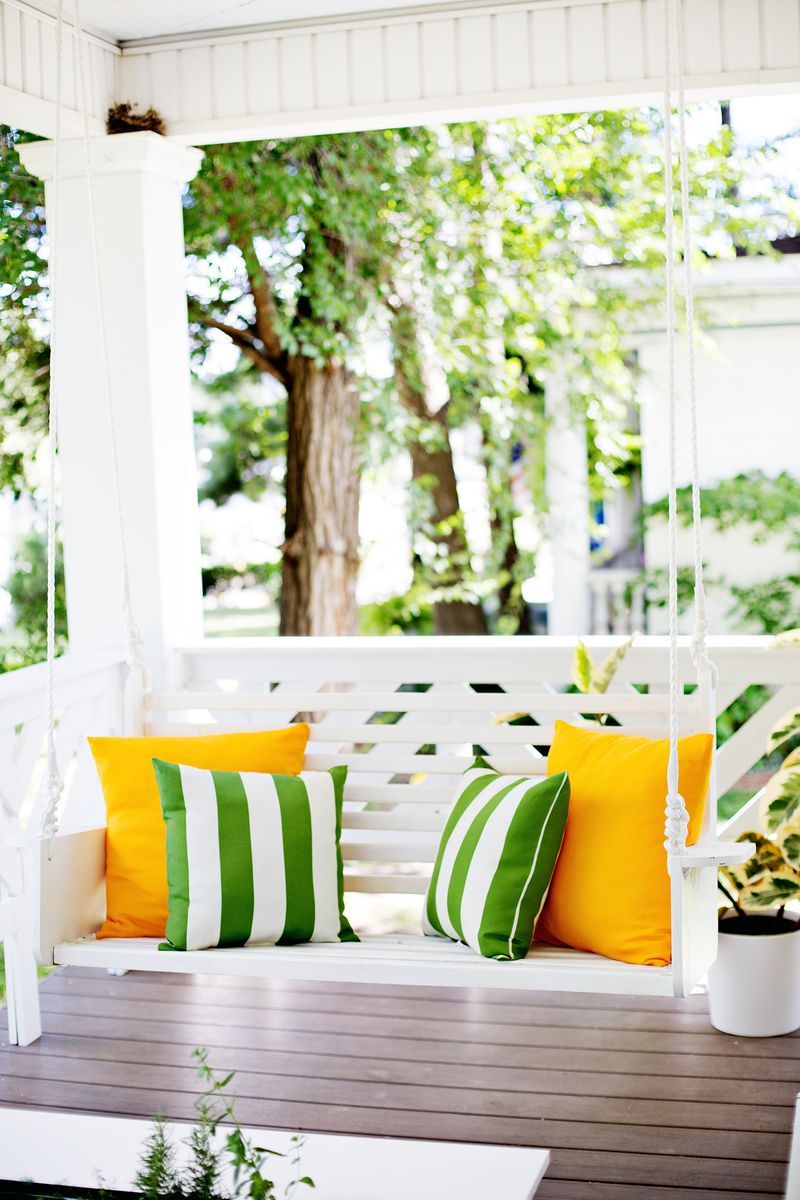 A white porch swing with colorful pillows