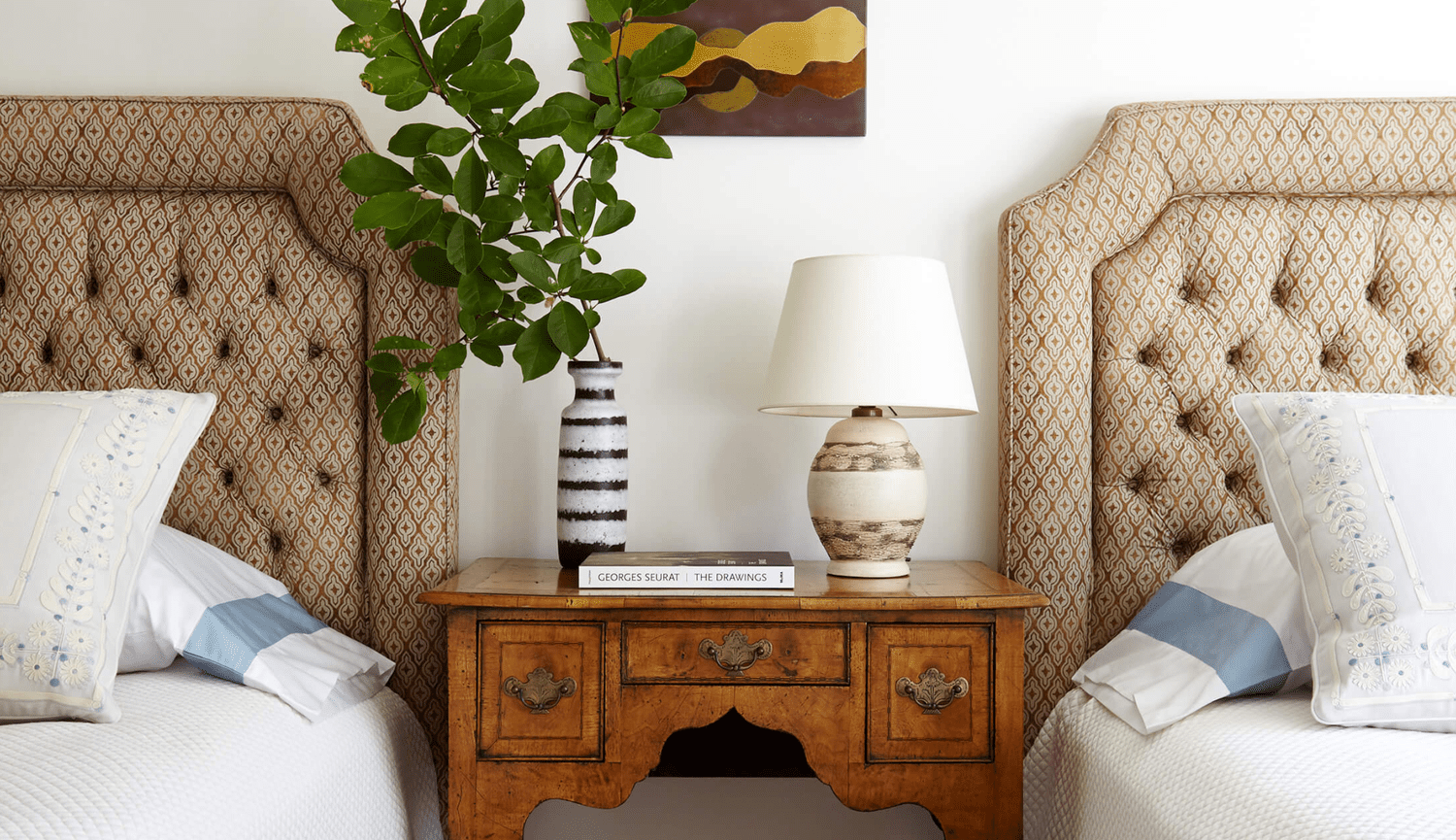 Une chambre à coucher avec des têtes de lit touffetées et une table de nuit antique