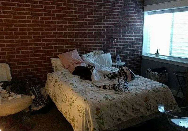 Teen girl's dark basement bedroom with red brick wall.