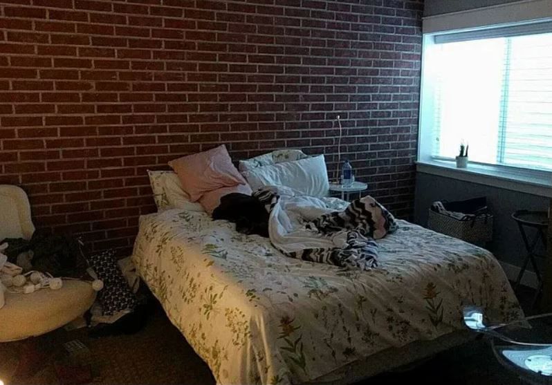 Quarto de uma adolescente no porão escuro com parede de tijolos vermelhos.