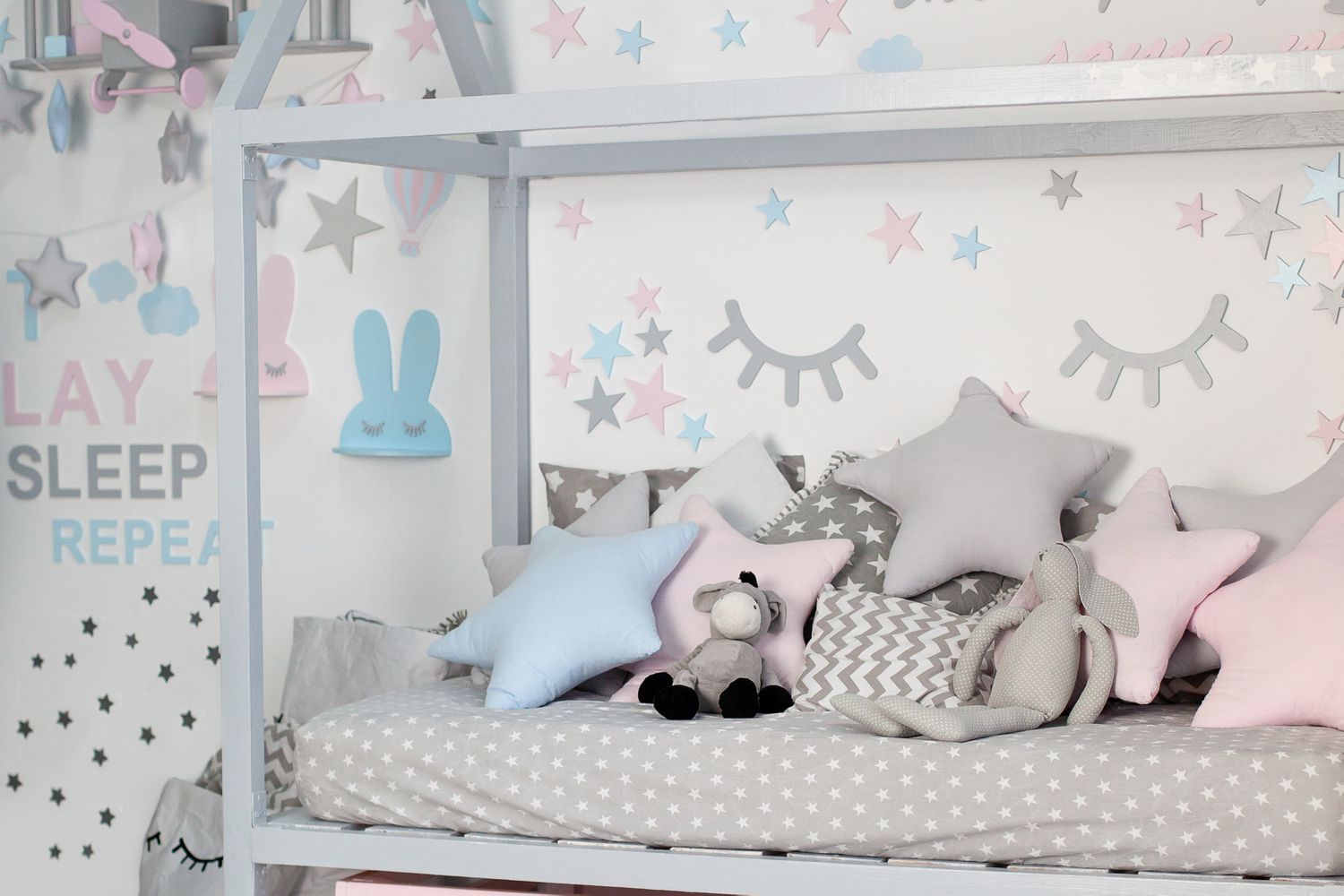 Kinderbett im sonnigen weißen Schlafzimmer. Kinderzimmer und Innenarchitektur. Bett für Baby oder Kleinkind Junge zu Hause. Bettzeug und Textilien für Kinderzimmer. Mittagsschlaf und Schlafenszeit. Kinderzimmer mit Kissen.