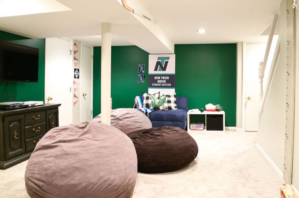 Espacio de reunión para adolescentes en el sótano con sillones bean bag y paredes verdes.