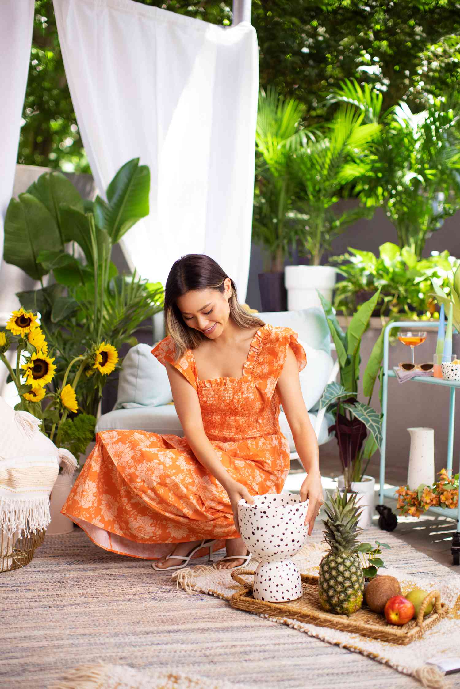 Jamie Chung arrangiert ein Tablett mit Früchten und Dekor auf einem Teppich in ihrem Hinterhof in Brooklyn