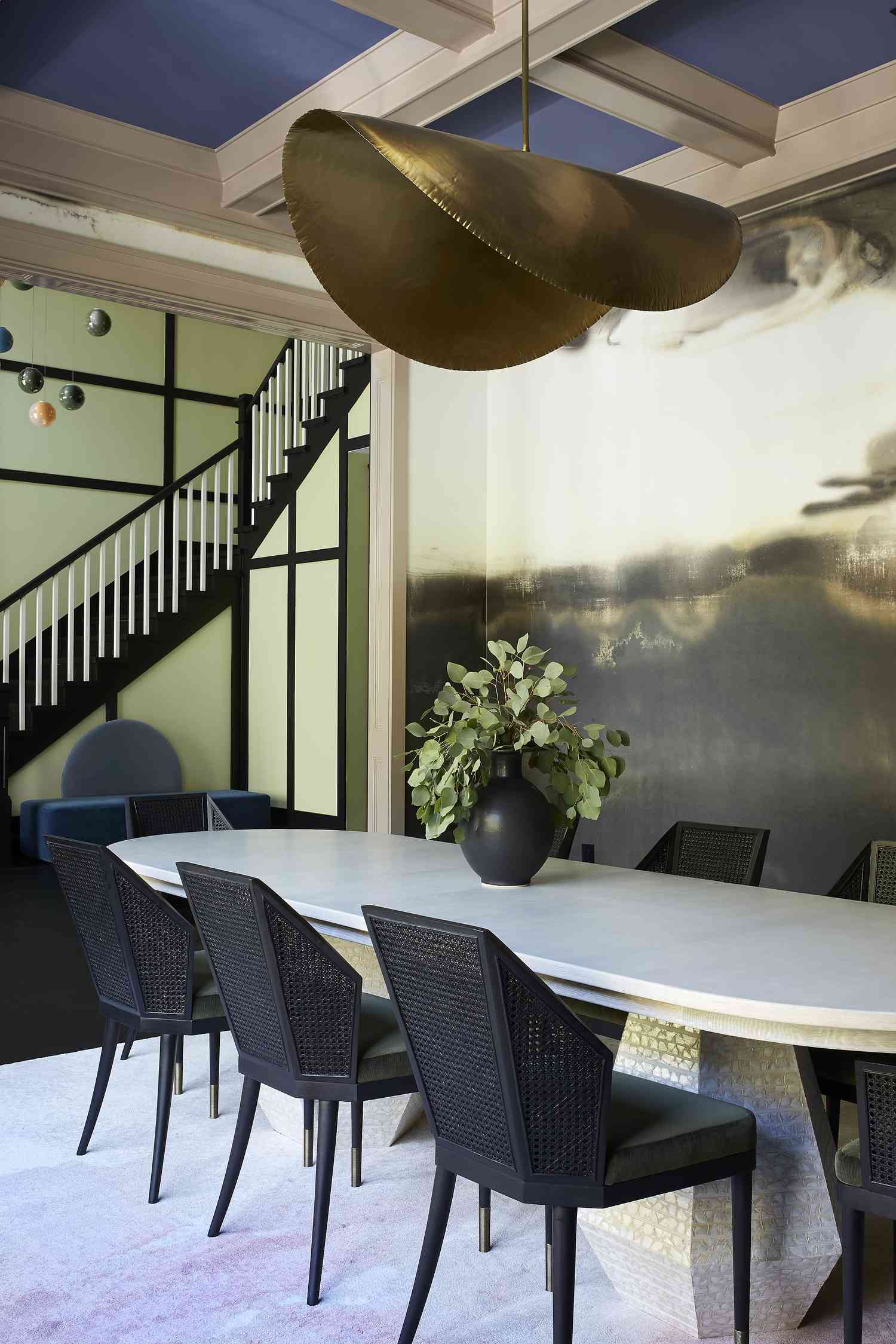 Comedor chic con una mesa blanca, sillas negras y una araña arquitectónica dorada