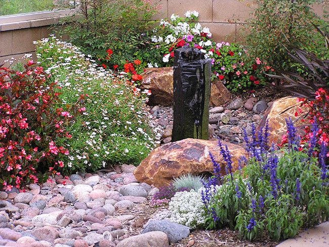 Round river rocks in a colorful desert garden with tall obsidian sculpture