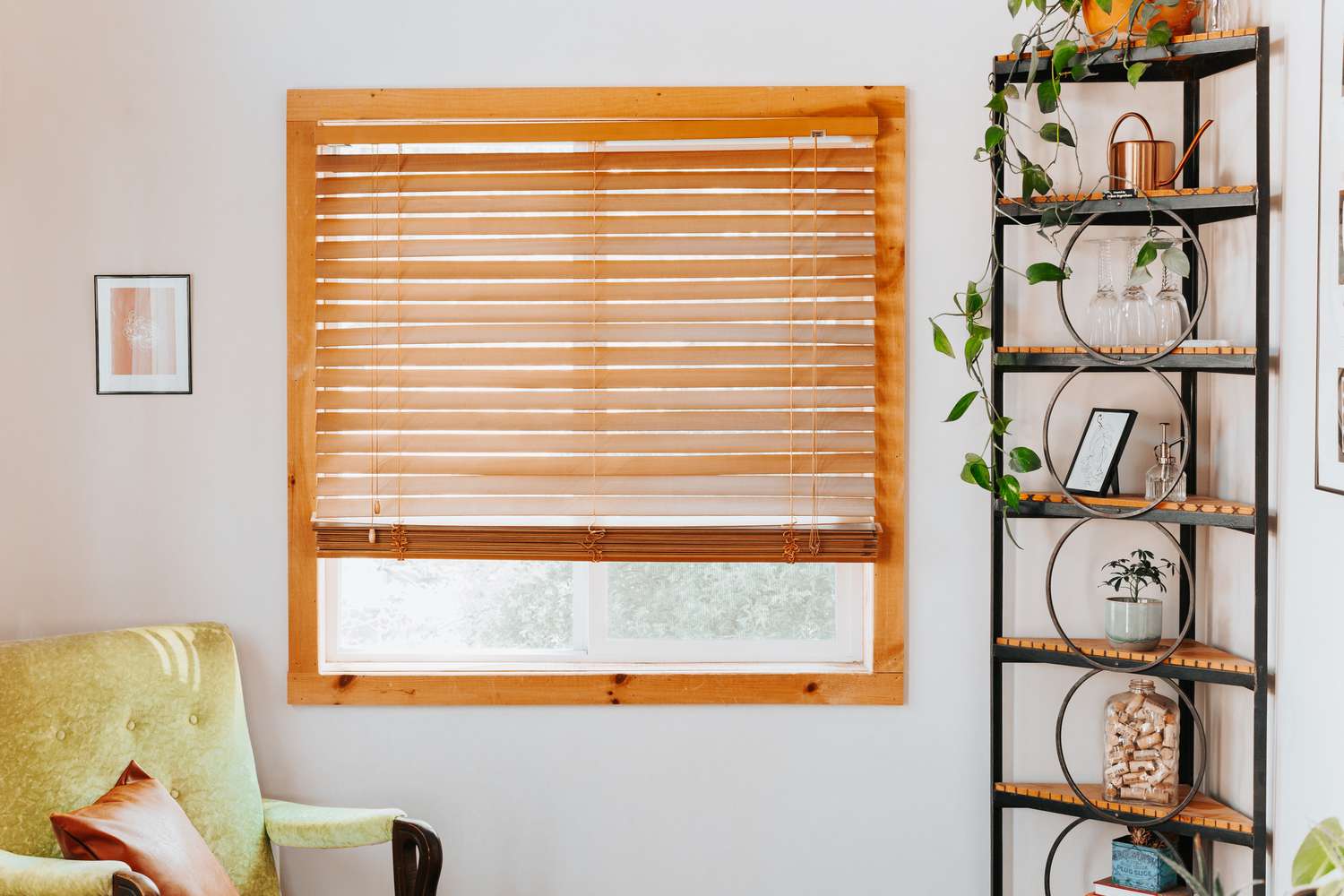 Persianas de madera cubriendo en su mayoría la ventana con un atril y un sofá de dos plazas en esquinas opuestas