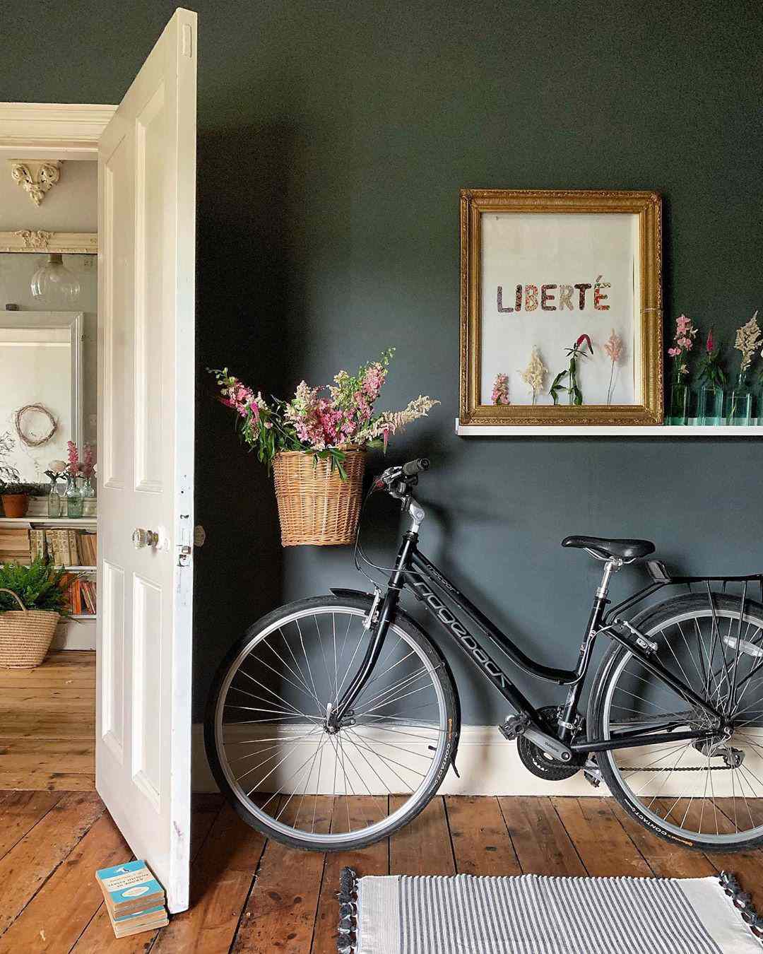 entrada con paredes gris oscuro y bicicleta con flores en la cesta 