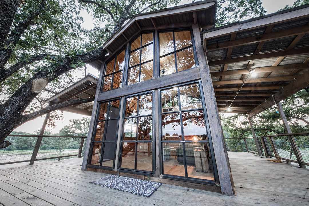 Casa na árvore com muitas janelas e uma varanda