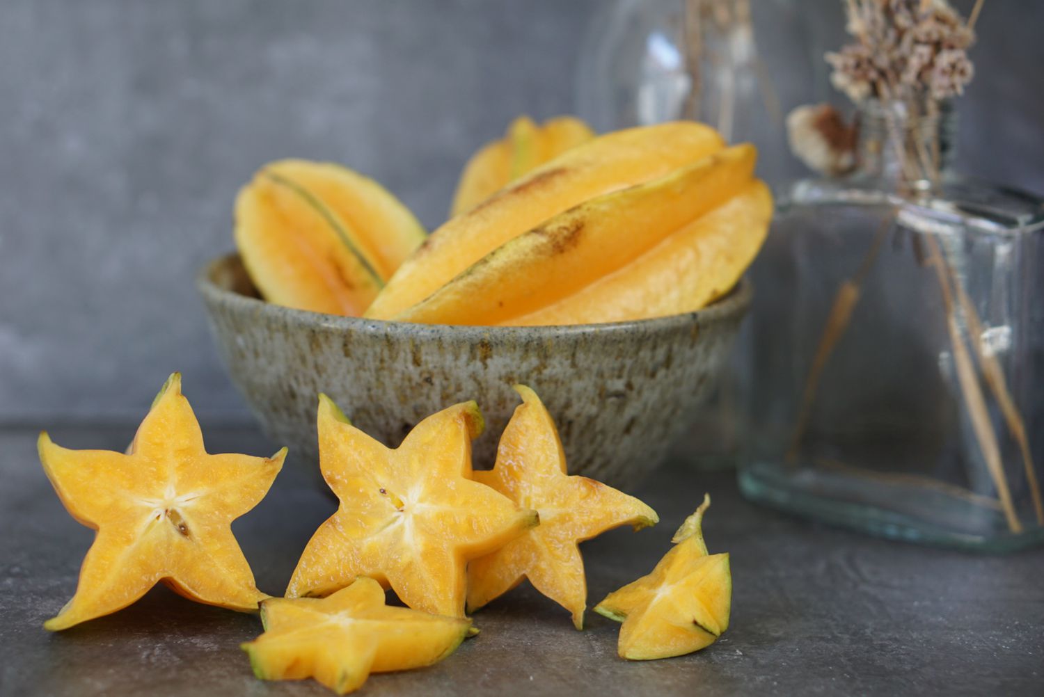 Carambola amarela em uma tigela e pedaços cortados em forma de estrela