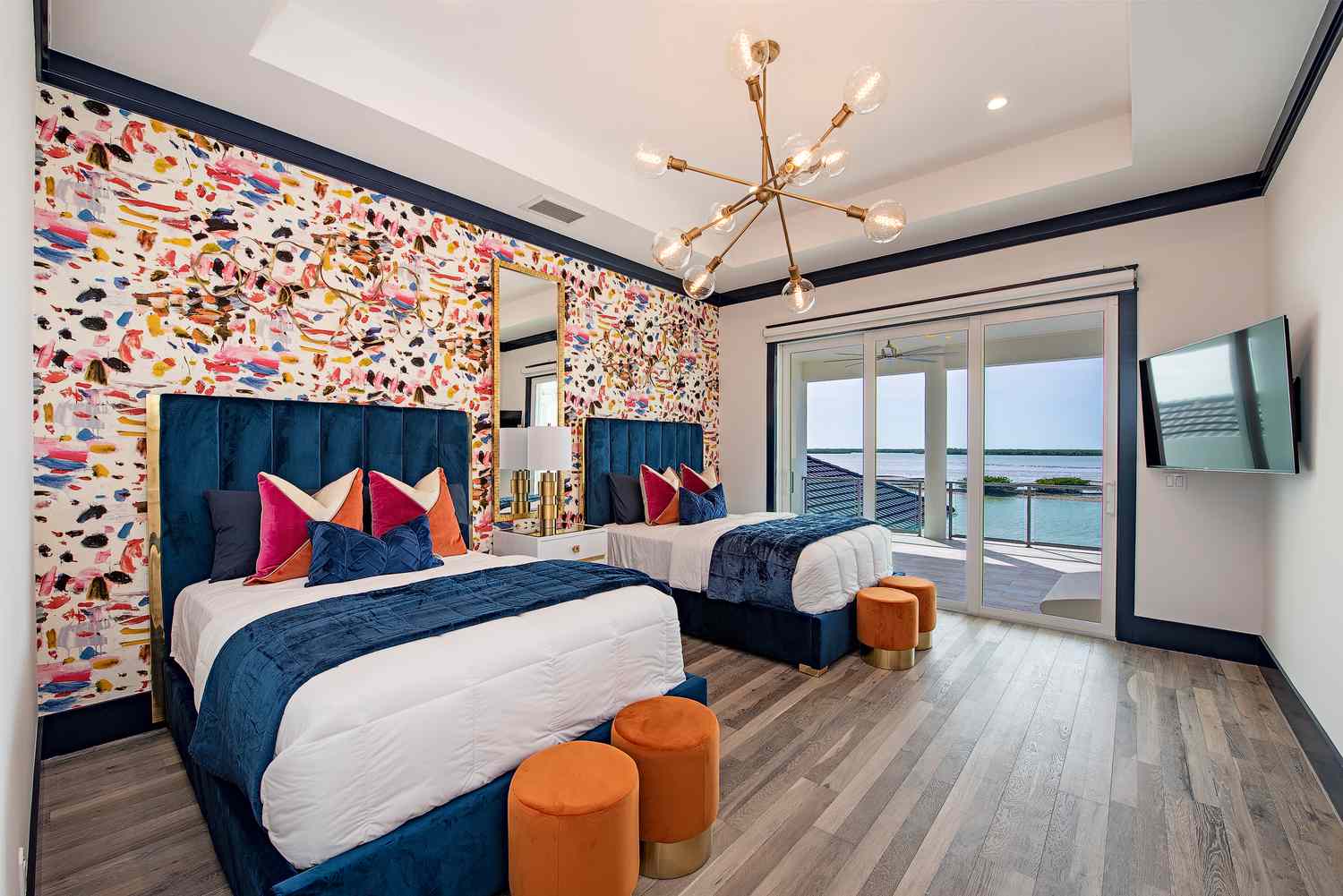 Um quarto com duas camas de casal e papel de parede colorido em uma parede de destaque