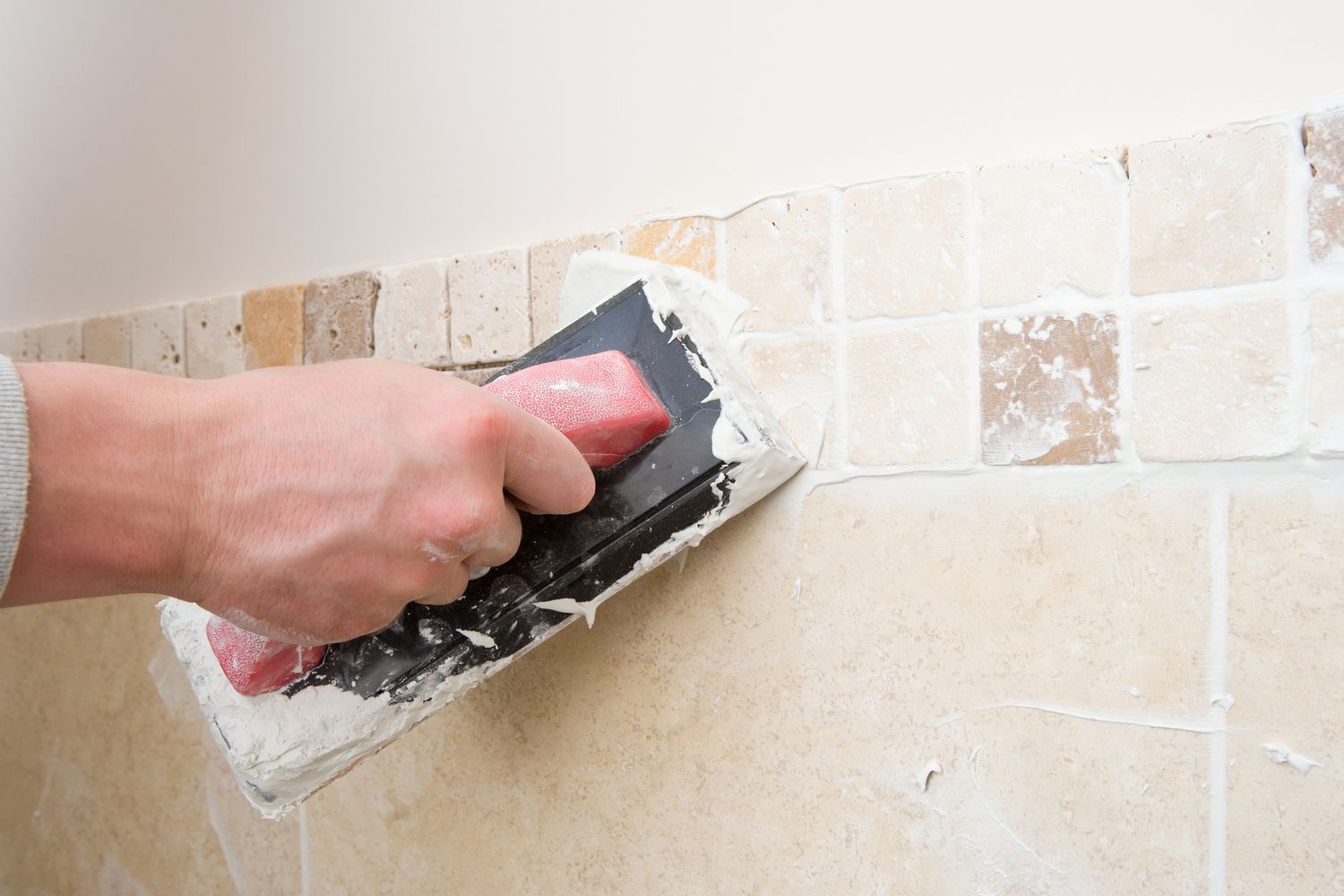 Person applying grout to tile