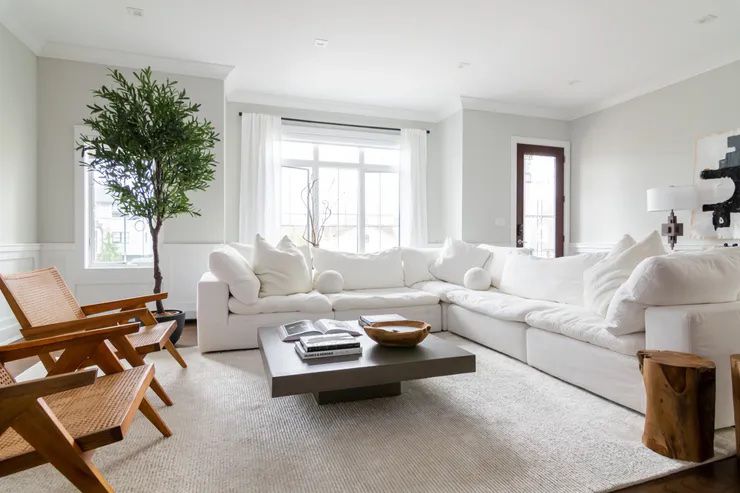 Ampla sala de estar com paredes e sofás totalmente brancos.