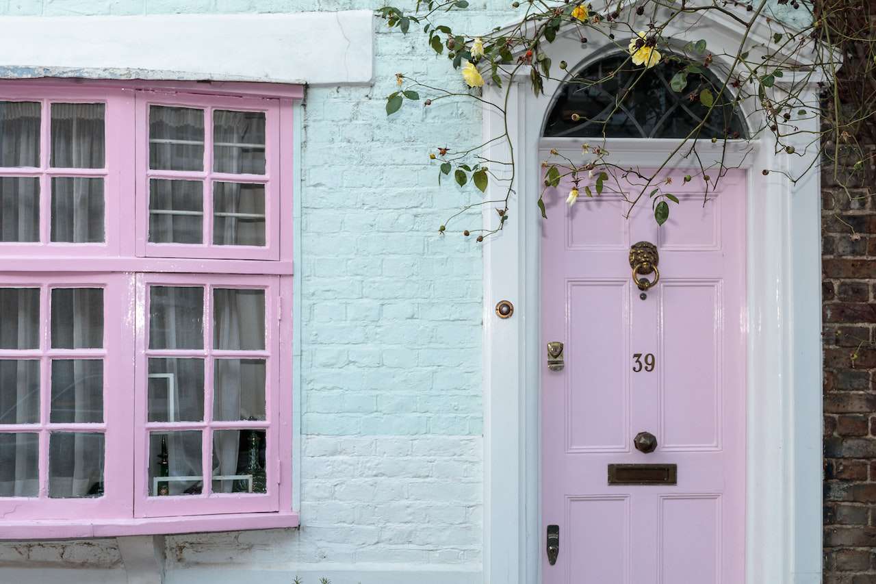 Blassblauer Backstein mit rosa Fenster und Tür