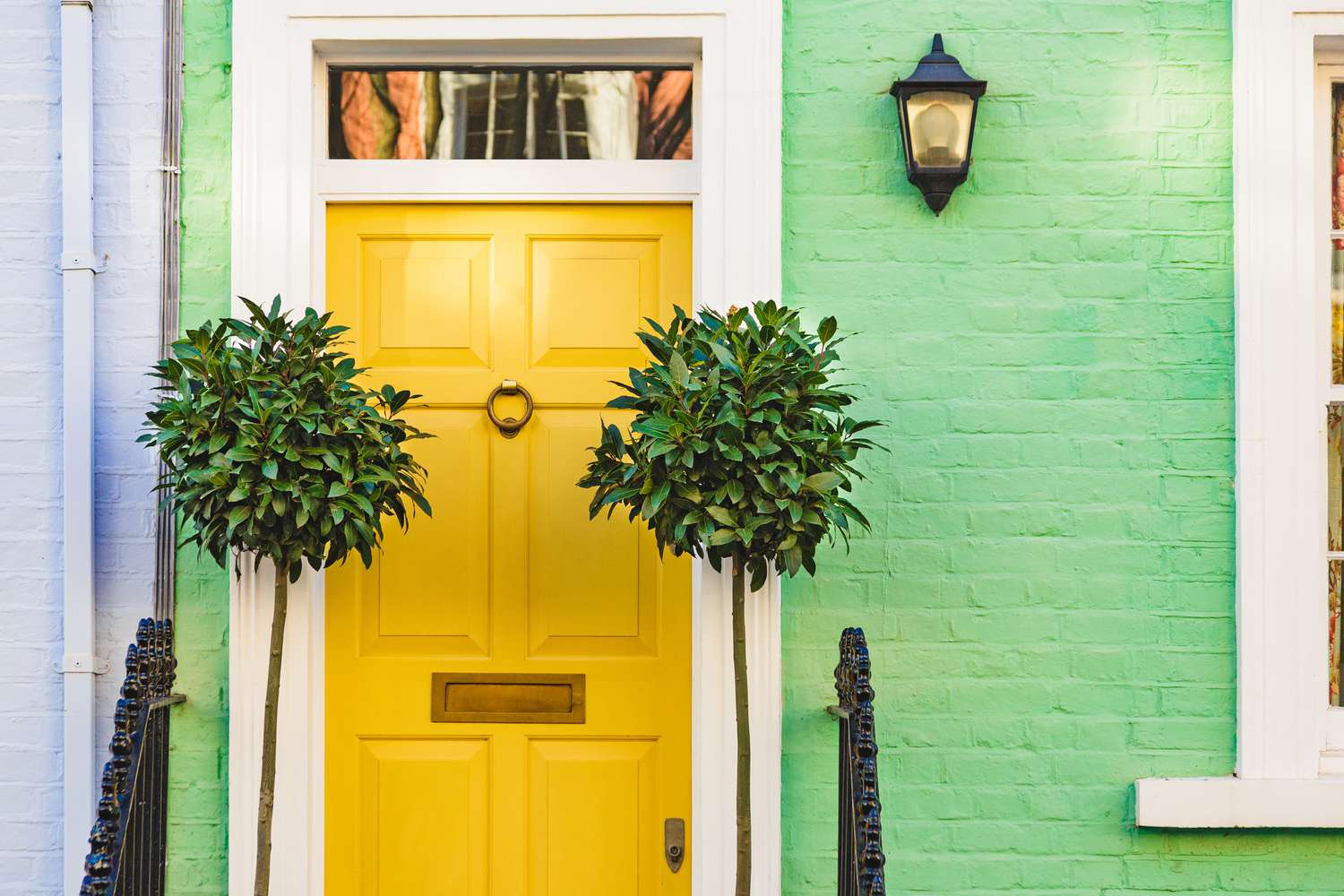 Fachada de ladrillos verdes con puerta amarilla