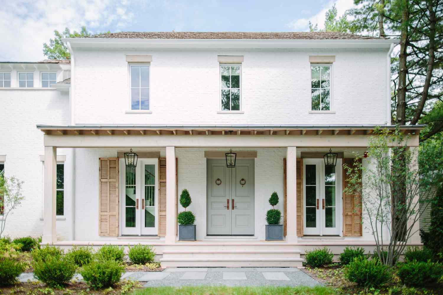 Casa de ladrillo blanco con contraventanas de madera