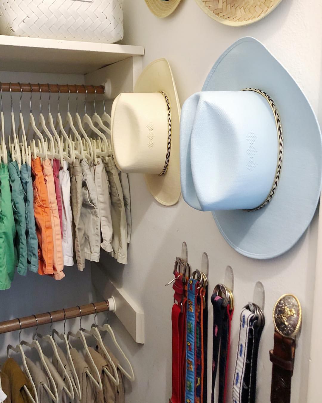 A closet with hanging belts and hats