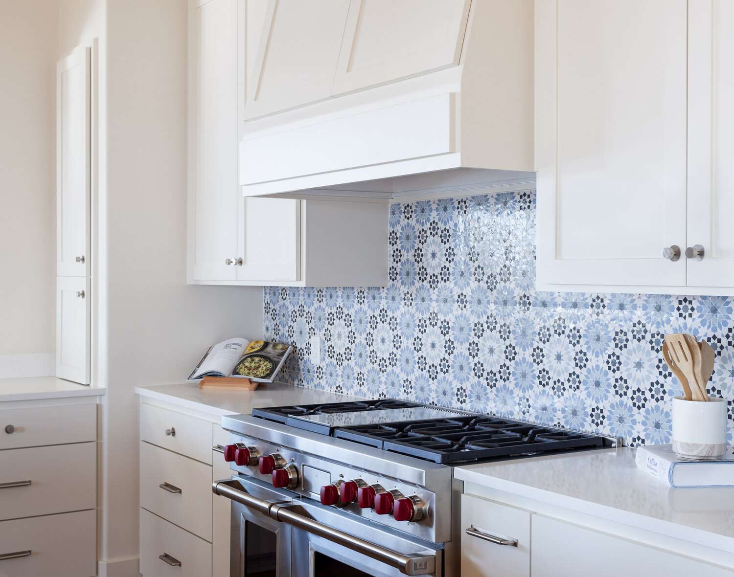 blue patterned tile backsplash with white cabinets