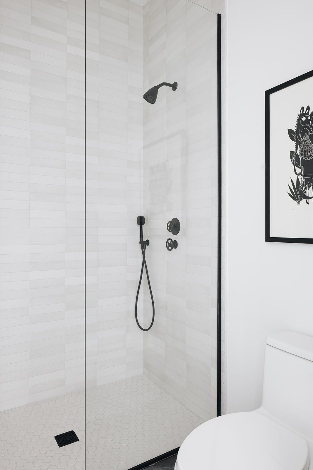 Schwarz-weiße Dusche mit Glastür und schwarzen Armaturen