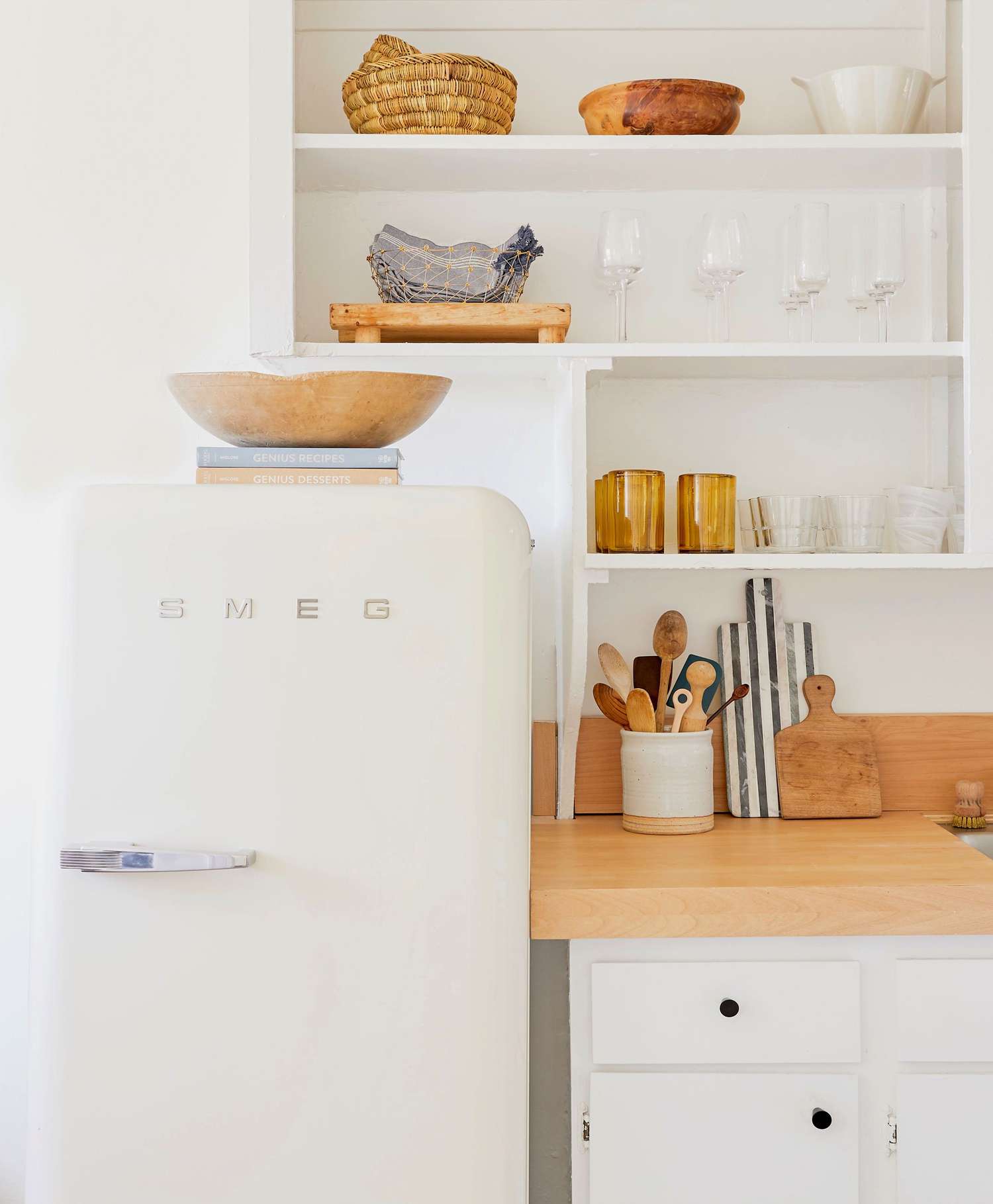 cozinha moderna branca com geladeira retrô, livros de receitas e tigela em cima da geladeira