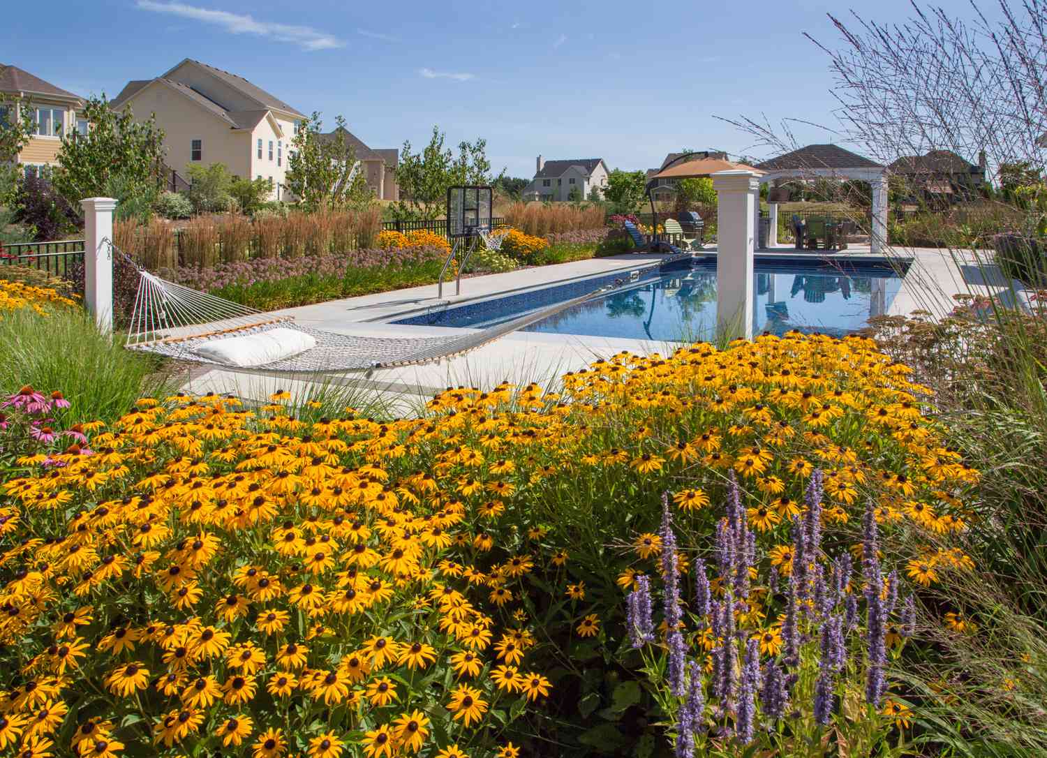 Hamaca de red junto a piscina y flores de jardín