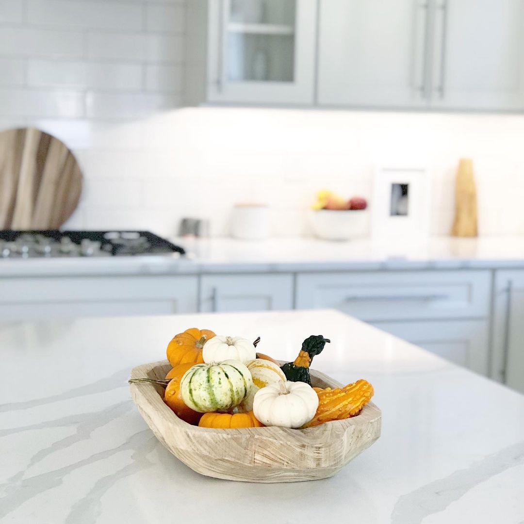 Citrouilles et courges dans un bol en bois sur un îlot de cuisine