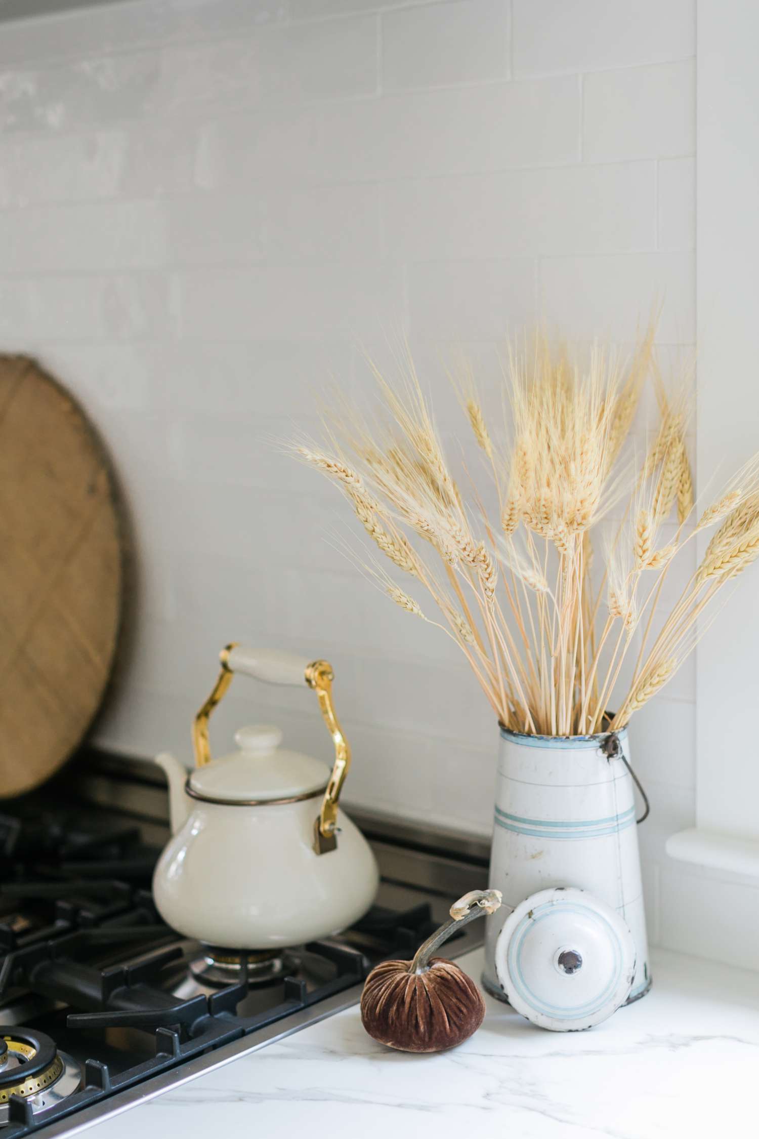 Getrockneter Weizen in einem Metallkrug und Samtkürbis auf einem Küchentisch