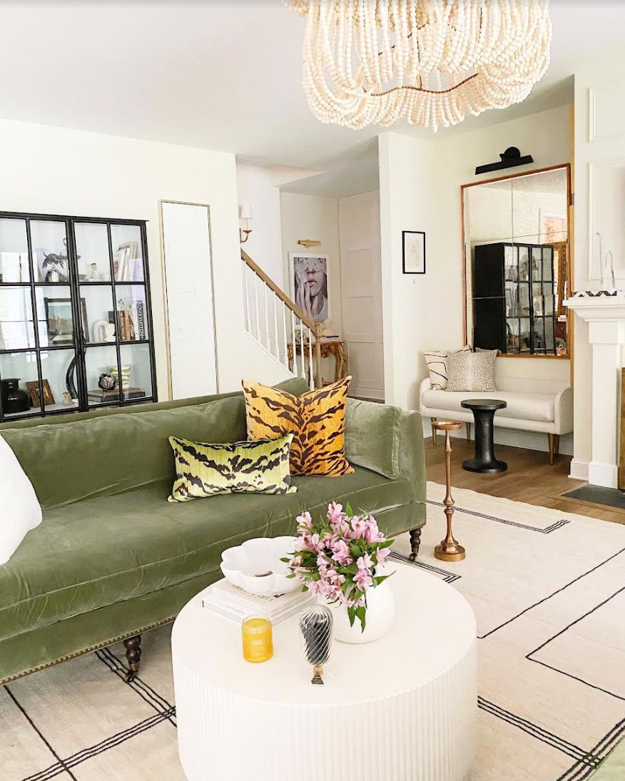 Elegantes Wohnzimmer mit olivgrüner Couch und orangefarbenem Kissen.