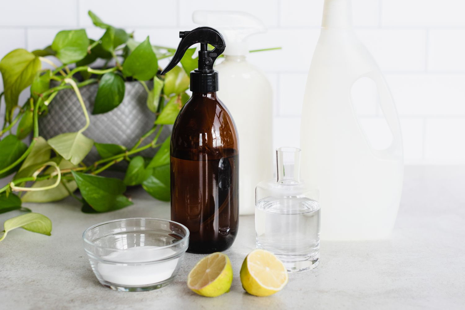 Botella de espadín marrón junto a rodajas de limón cortadas delante de botellas de detergente y bol de cristal con lejía 