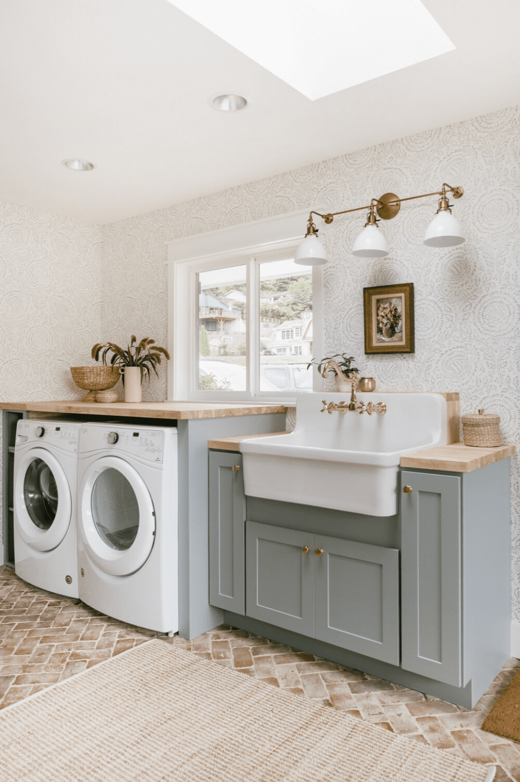 Subtile Blumentapete in einer Waschküche mit Messing-Wandleuchte, grauen Schränken und Arbeitsflächen aus Butcherblock