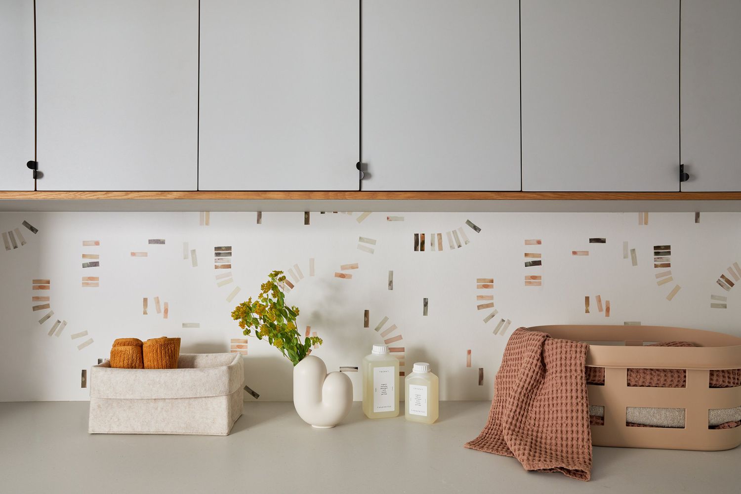 Papel de parede minimalista usado em vez de um backsplash de azulejo em uma lavanderia