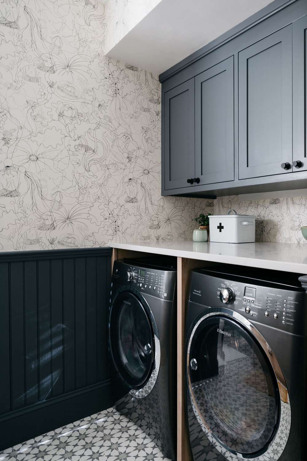 Schwarz-weiße Blumentapete in einer Waschküche mit grauen Schränken