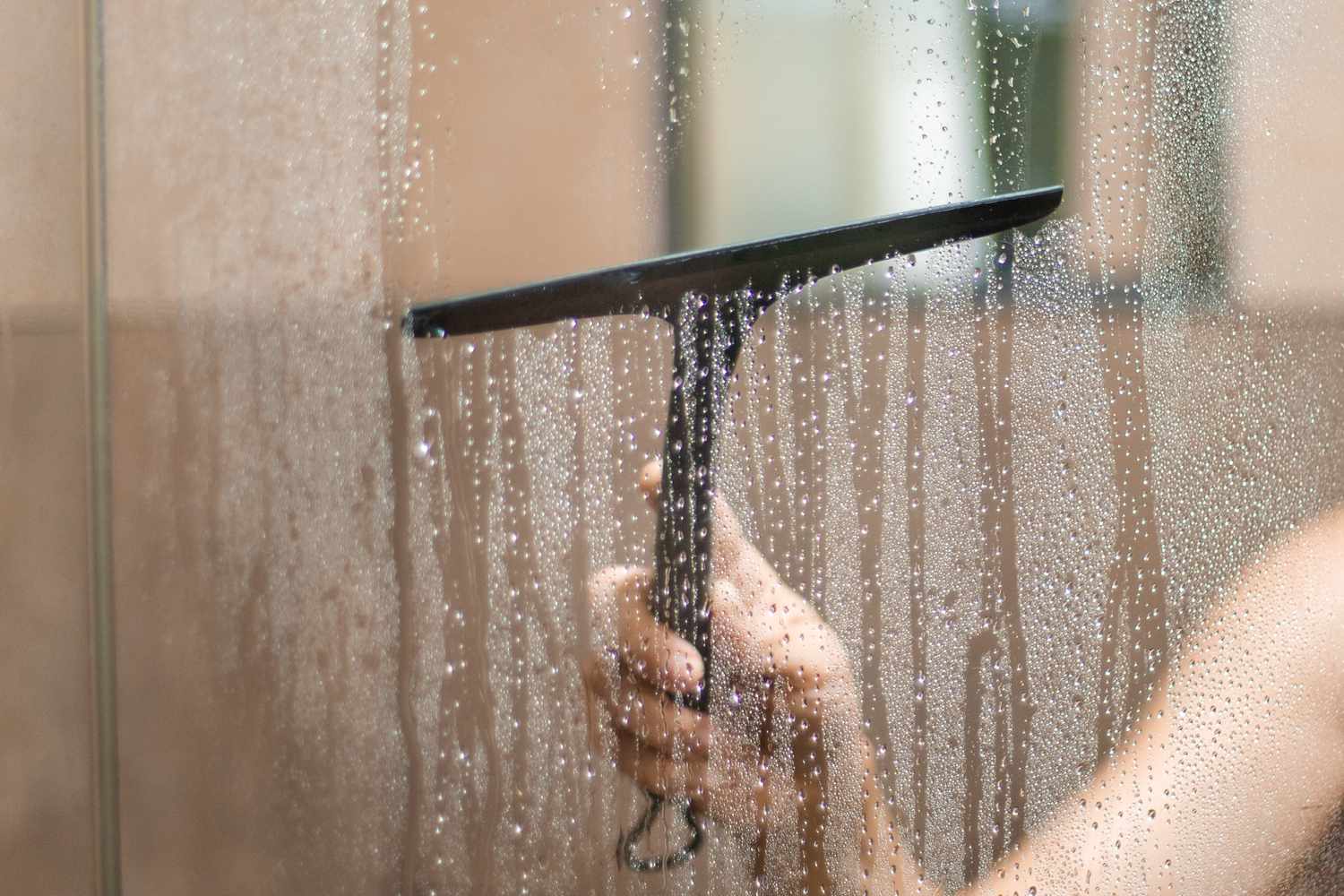wiping down shower doors with a squeegee