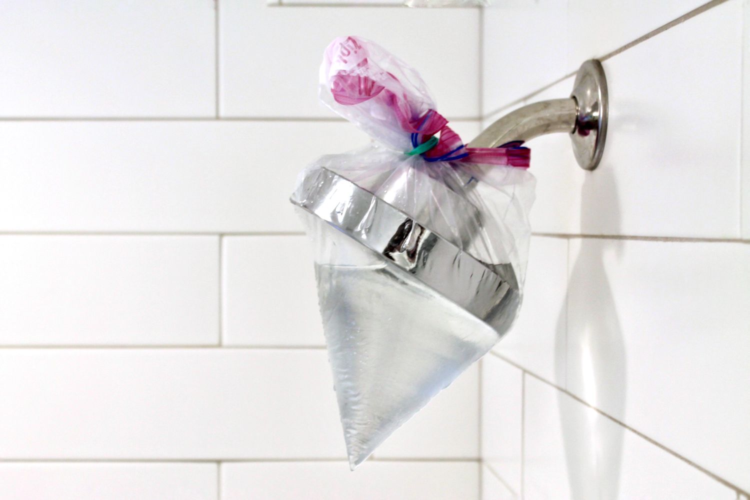 plastic bag filled with vinegar tied around a shower head