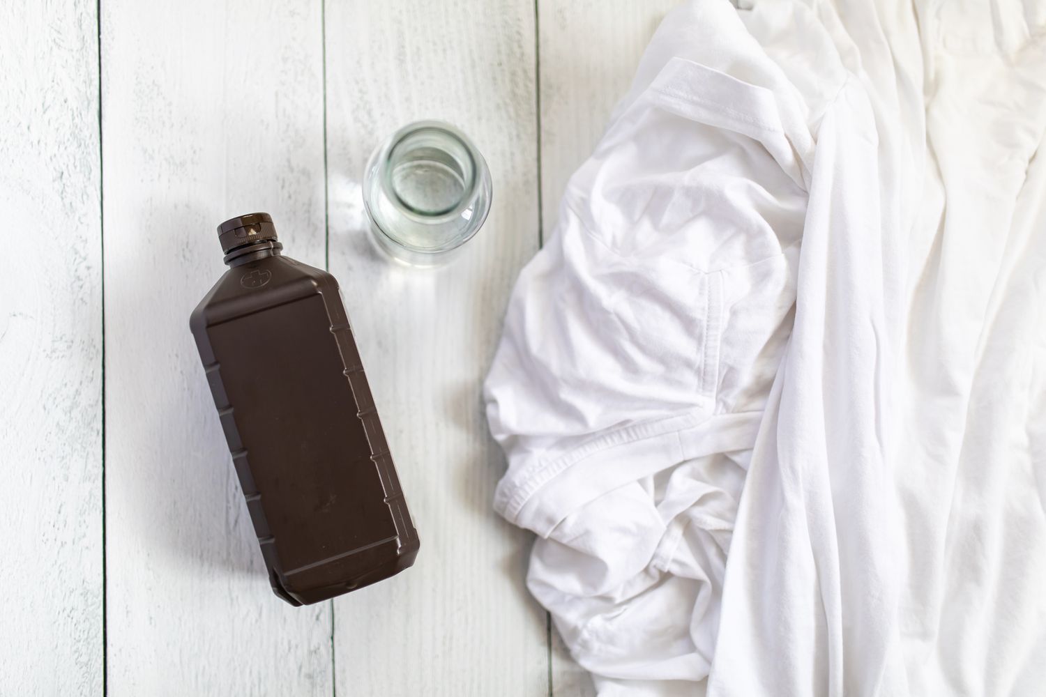 botella de agua oxigenada junto a ropa blanca