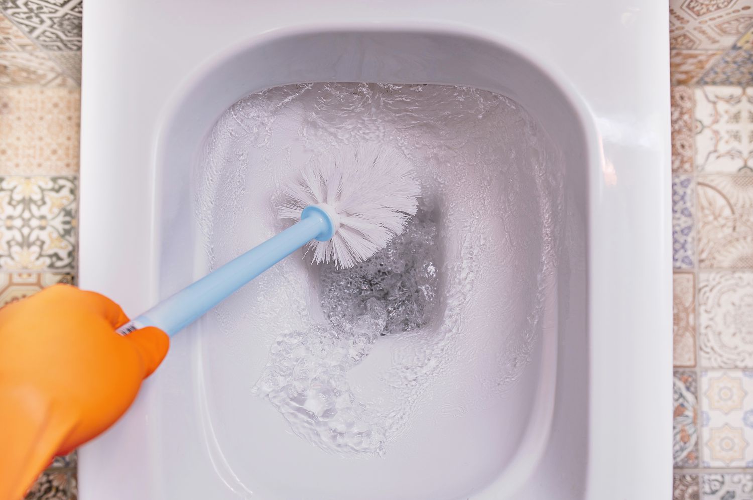 Toilet bowl brush being used to scrub a toilet