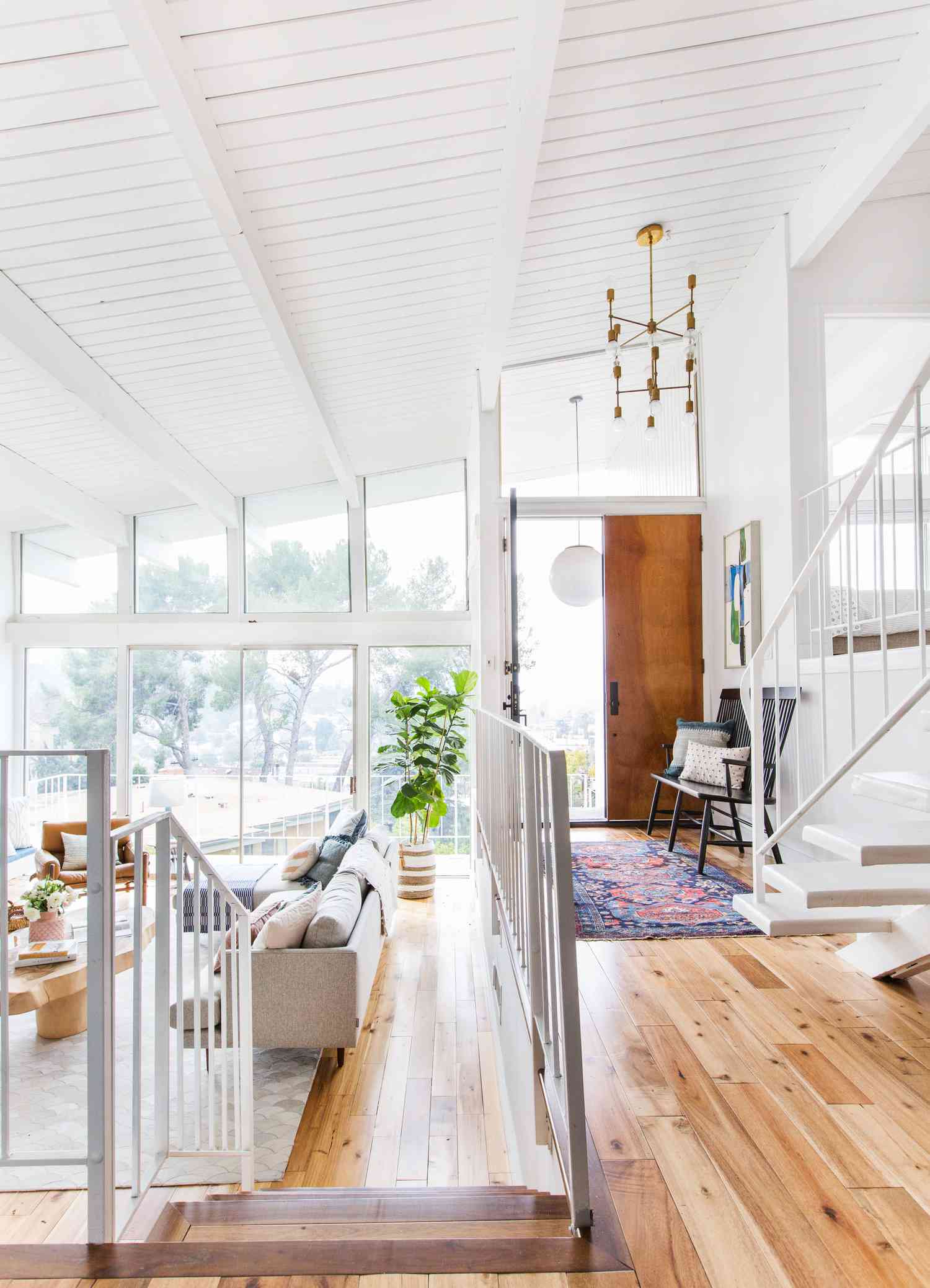 Ein weißes Zimmer hat einen Holzfußboden, der Eingangsbereich ist mit einem langen hellen Teppich ausgelegt