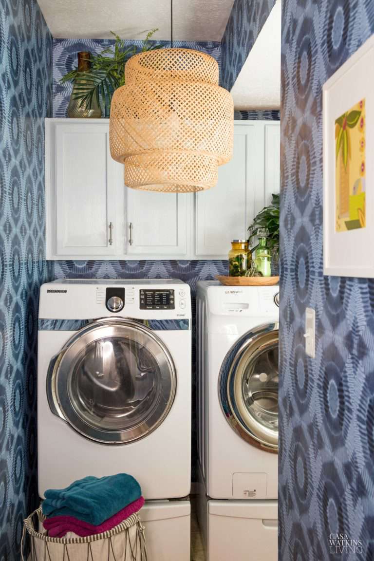 Waschküche mit weißen Schränken, blauer Grafiktapete und Rattan-Pendelleuchte