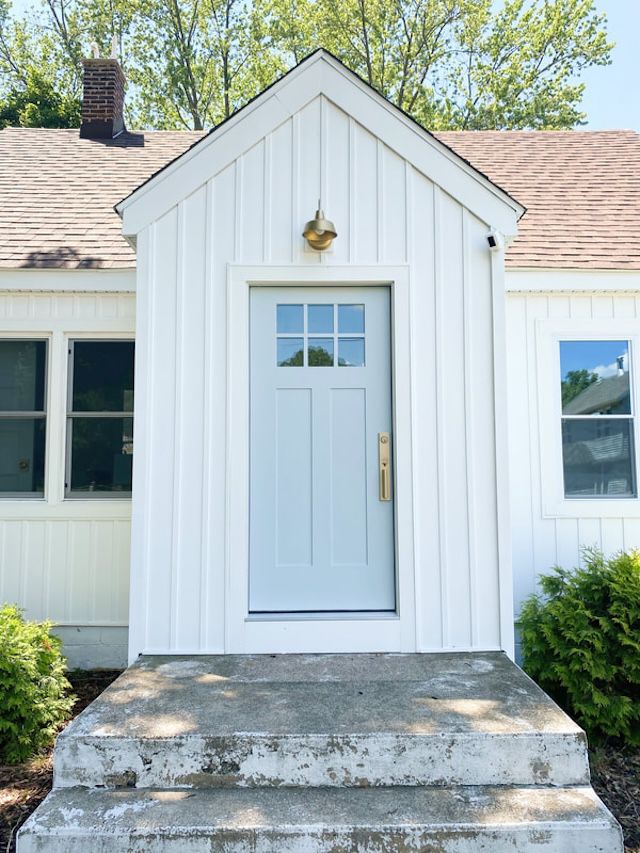 Blaue Haustür an weißem Bauernhaus mit Messingbeschlägen