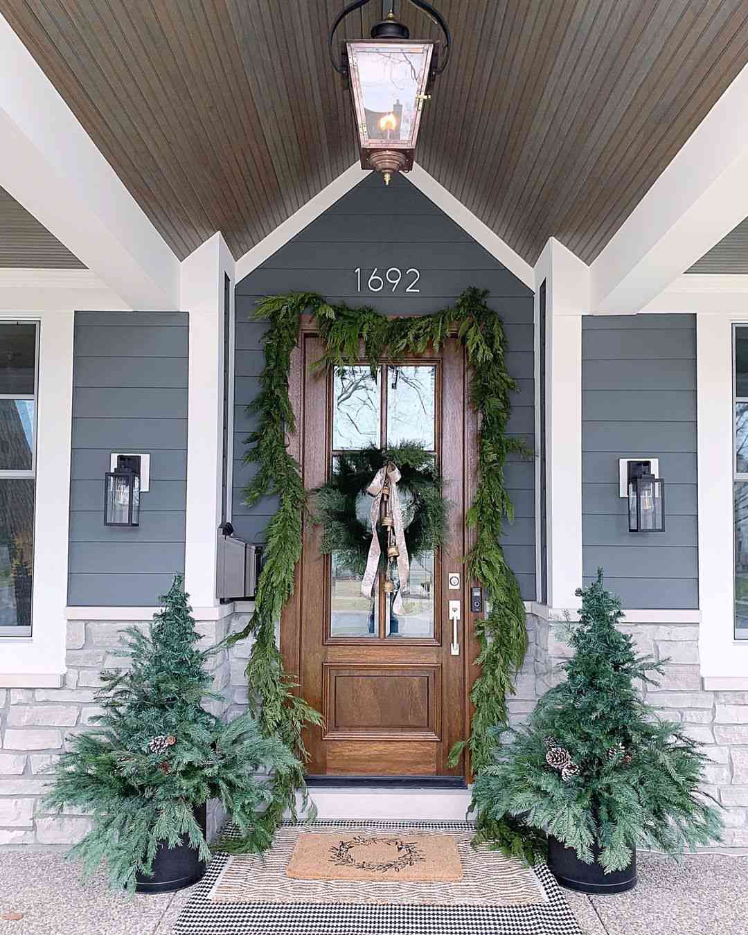 Front door and porch decorated for Christmas with live greenery