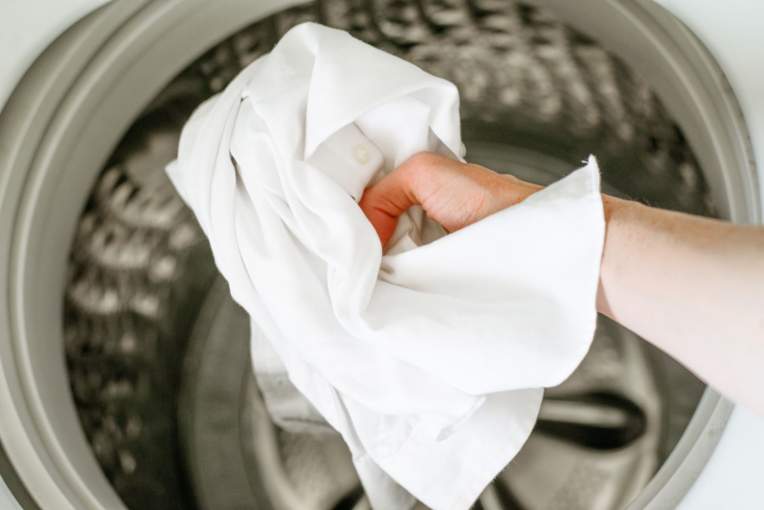 Camisa branca com botões colocada na máquina de lavar