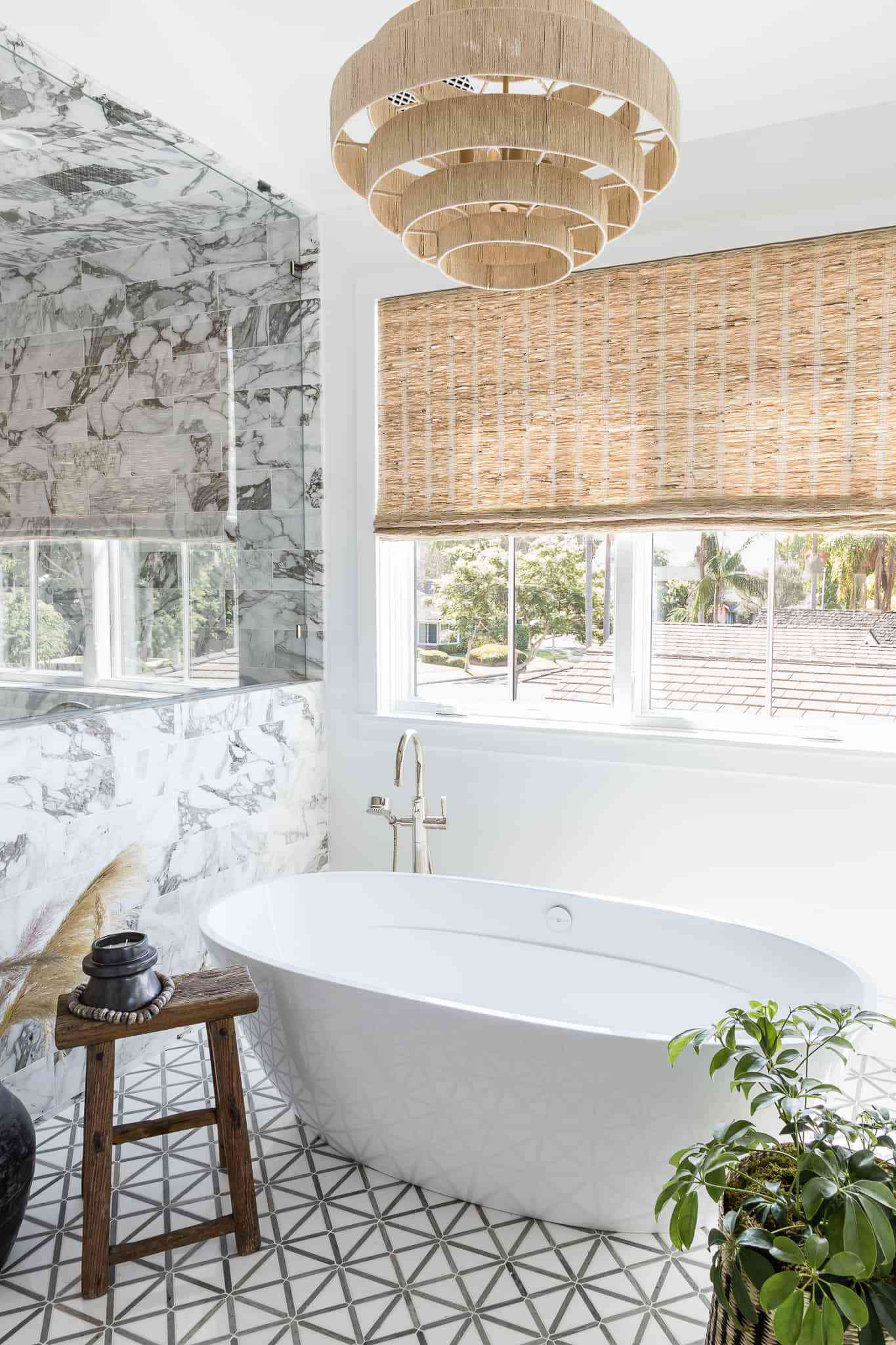 Um banheiro com paredes de mármore, pisos de azulejos estampados, um lustre de tecido e persianas de tecido combinando