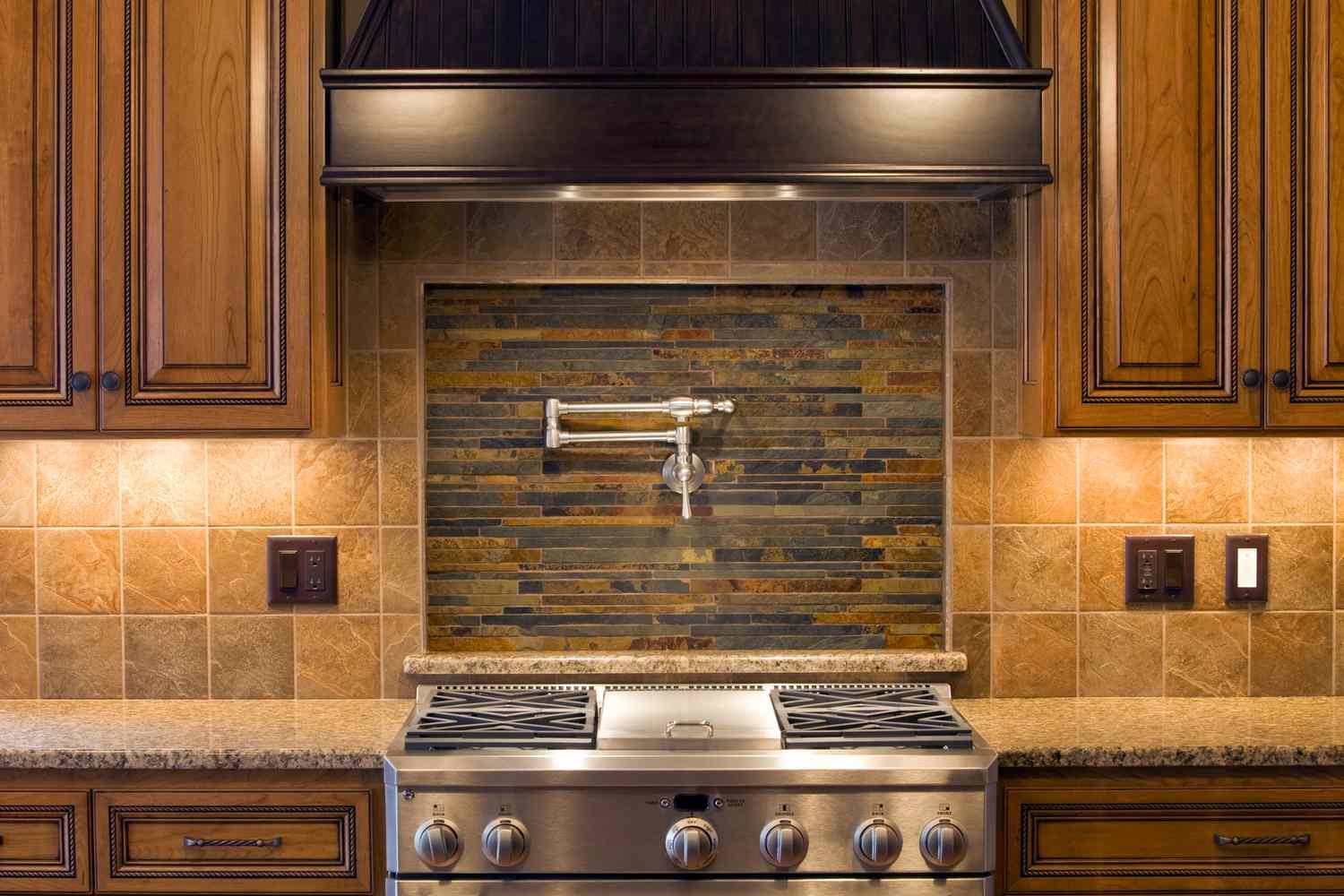 Cuisine avec placards en bois brun et mur en carreaux architecturaux derrière la cuisinière