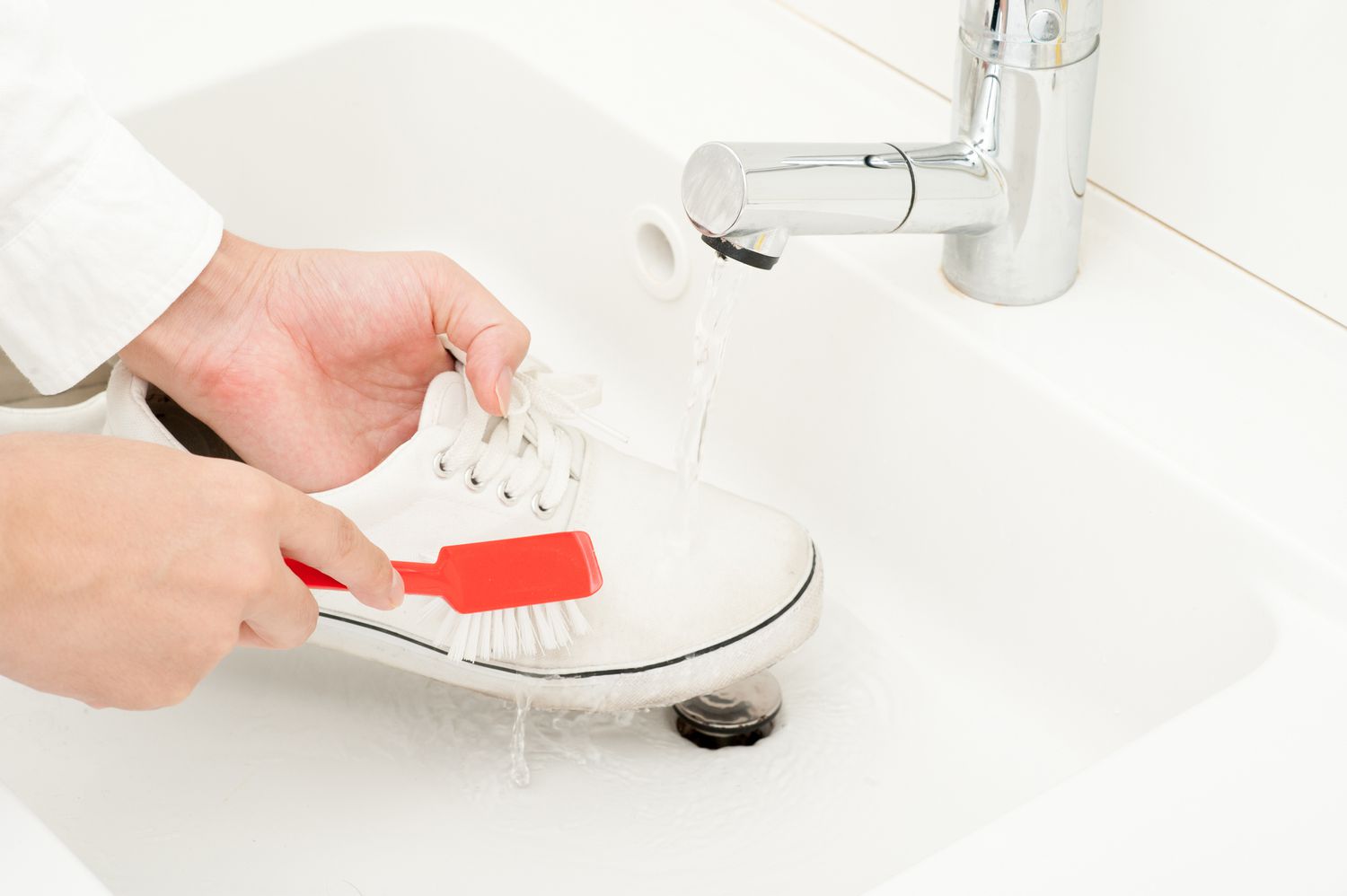 Ein Paar weiße Schuhe im Waschbecken reinigen