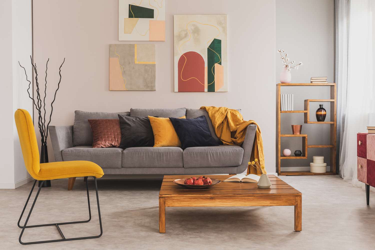 table basse en bois et chaise jaune devant un canapé gris avec des coussins dans un salon tendance