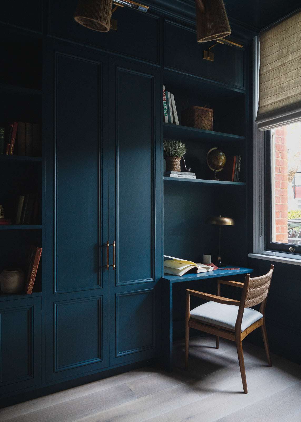 Armário embutido azul escuro e estantes de livros com escrivaninha