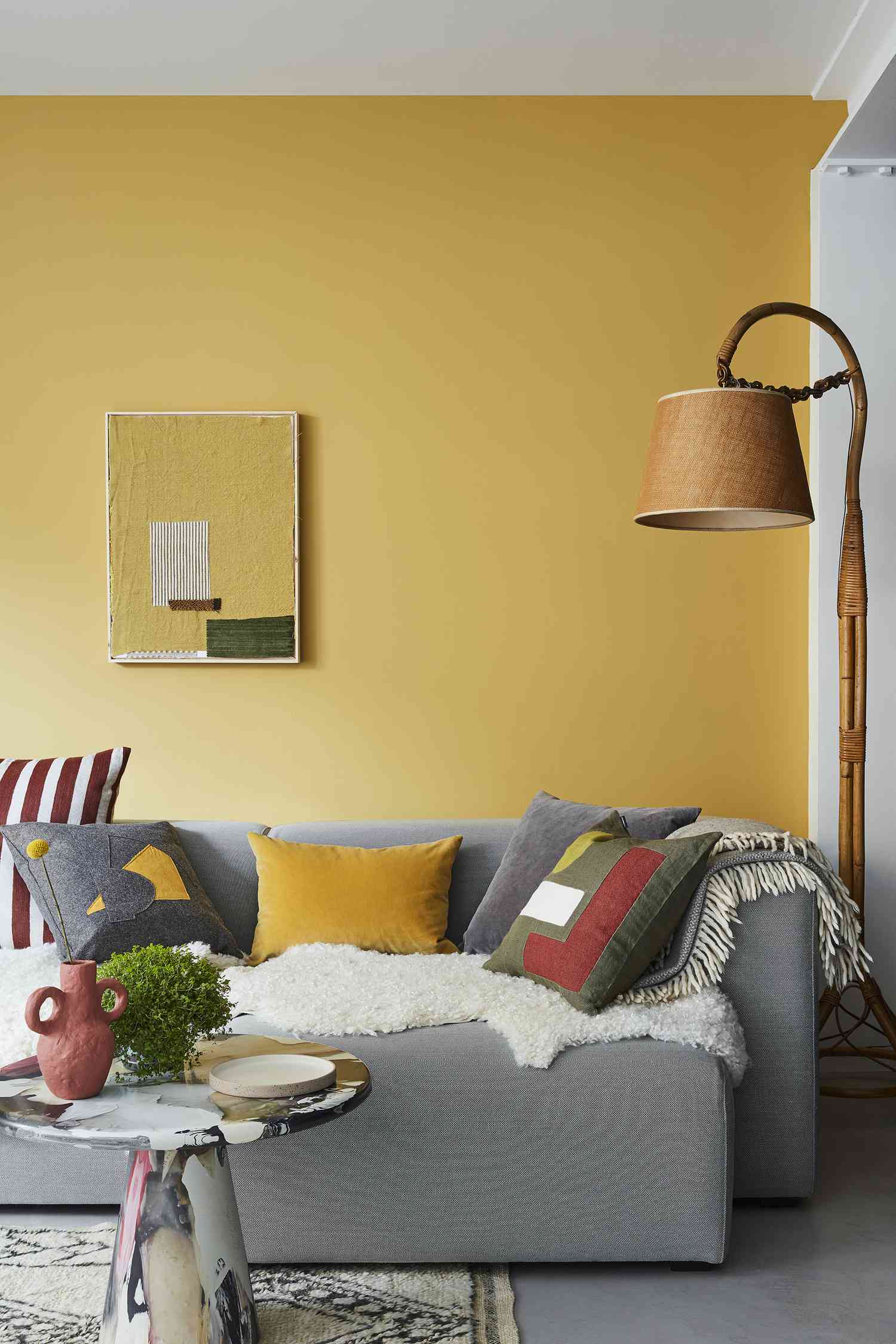 Gelbe Wand und graues Sofa