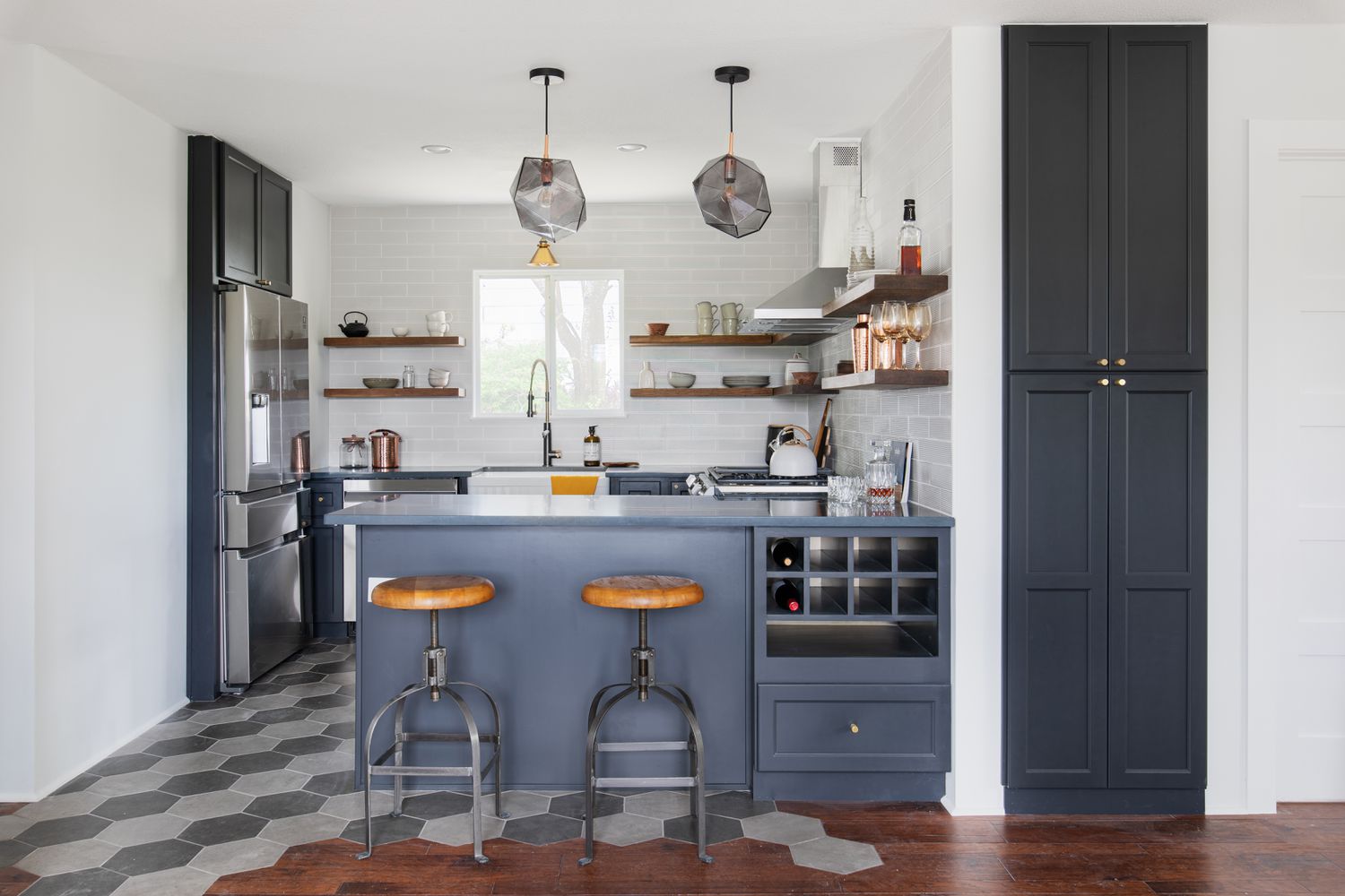 Um piso de cozinha de ladrilhos cinza escuro e cinza claro é combinado com armários azuis escuros